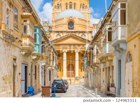 View of the Basilica of Christ the King in Paola through a narrow street with traditional Maltese houses, Tarxien, Malta 124965311
