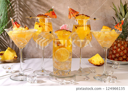 Various alcoholic cocktails with slices of mango, pineapple and ice in glasses with rims and umbrellas. Concept of a tropical party and relaxation. Advertising business card for a bar menu. 124966135
