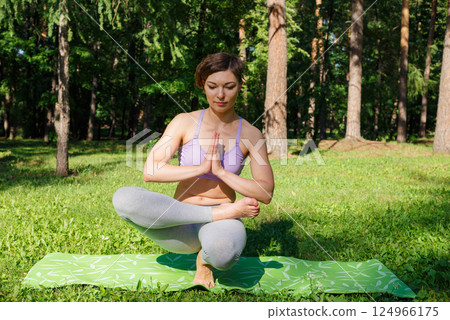 Beautiful girl practices yoga in the park. Beautiful girl practices yoga in the park. 124966175