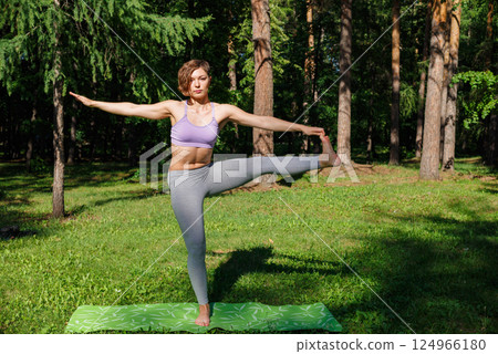 Beautiful girl practices yoga in the park. 124966180