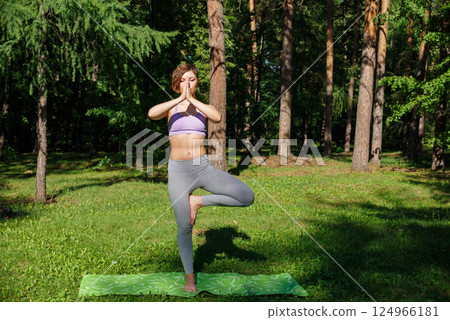 Beautiful girl practices yoga in the park. 124966181