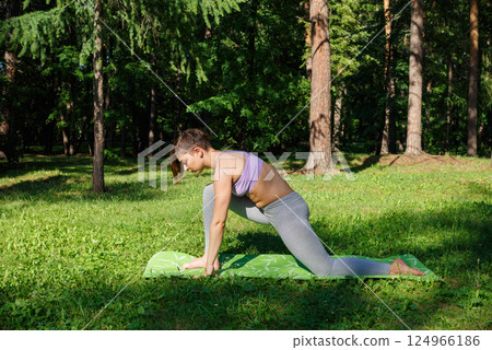 Beautiful girl practices yoga in the park. Beautiful girl practices yoga in the park. 124966186