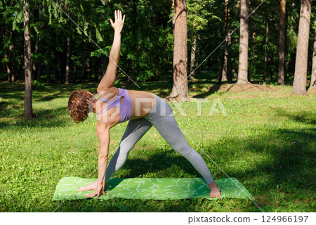 Beautiful girl practices yoga in the park. Beautiful girl practices yoga in the park. 124966197