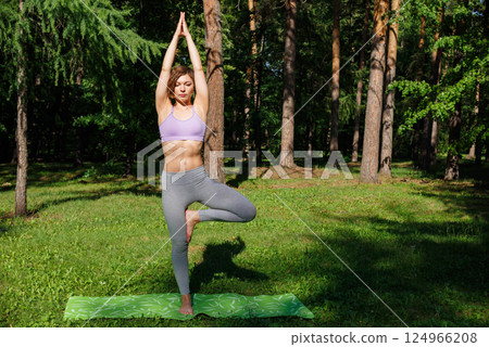 Beautiful girl practices yoga in the park. 124966208