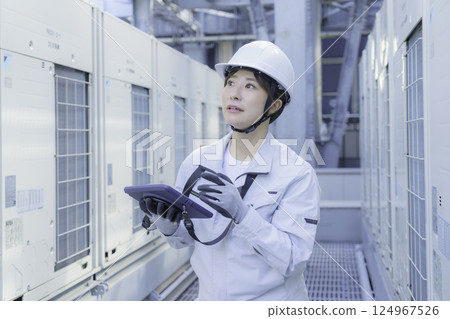 A young female worker carrying out inspection work on the roof of a building. Photo courtesy of Tokyo Electronics College, Denpa Gakuen Corporation. 124967526
