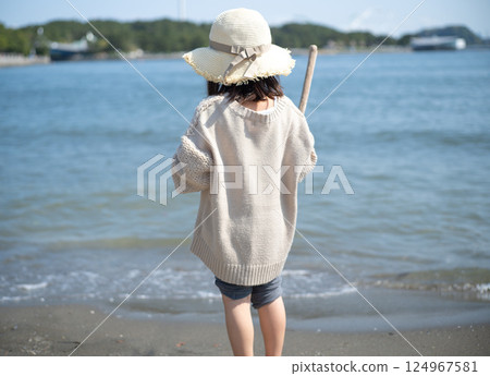 A child standing on a sandy beach 124967581