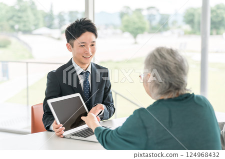 一位商人用筆記型電腦向一位高級女士提供建議(資產管理、保險、金融) 一位商人用筆記型電腦向一位高級女士提供建議(資產管理、保險、金融) 124968432