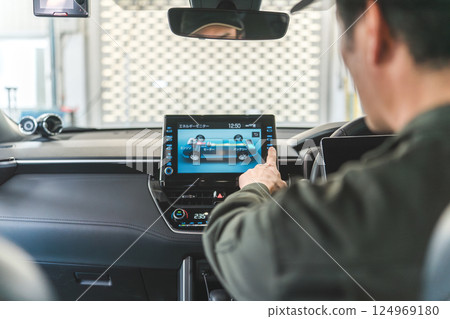 Male auto mechanic using a tablet device inside a car Male auto mechanic using a tablet device inside a car 124969180