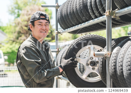 一名男性機械師從輪胎架上搬運鑲釘輪胎 124969439