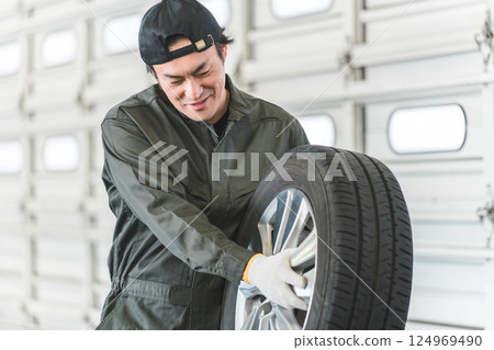 在汽車修理廠運輸輪胎的男性機械師(體力勞動、苦力勞動、繁重工作、背痛) 在汽車修理廠運輸輪胎的男性機械師(體力勞動、苦力勞動、繁重工作、背痛) 124969490