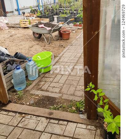 Farmyard with wheelbarrow and fruit tree seedlings in the background, real shot 124969729