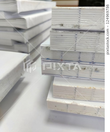 Close-up, a stack of glued book blocks prepared for binding in a printing house, vertical Close-up, a stack of glued book blocks prepared for binding in a printing house, vertical 124969786