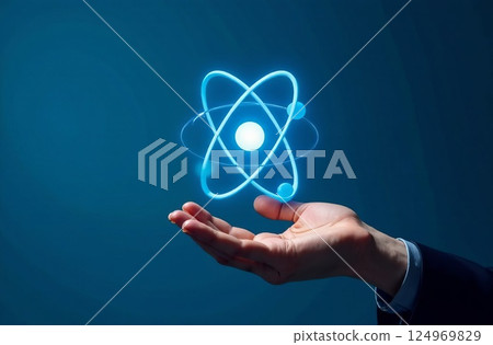 Bussinessman hand holding an atom icon on a blue background, concept of future technology, infinite energy Bussinessman hand holding an atom icon on a blue background, concept of future technology, infinite energy 124969829