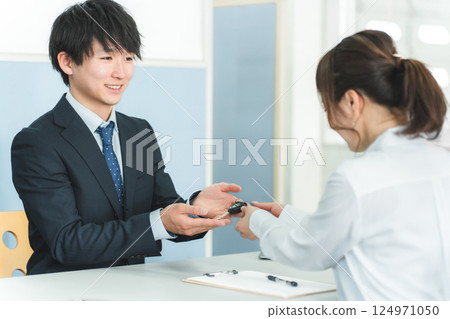 接待處,一名男工作人員及一名女顧客遞交車鑰匙 接待處,一名男工作人員及一名女顧客遞交車鑰匙 124971050