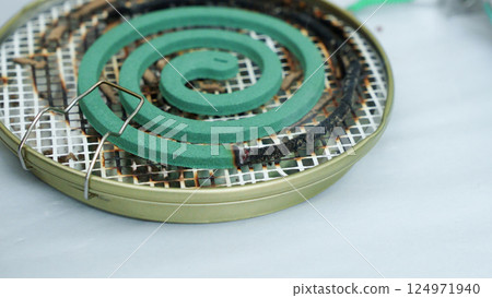 Burning green spiral mosquito repellent coil and red fire with white smoke on dark background. 124971940