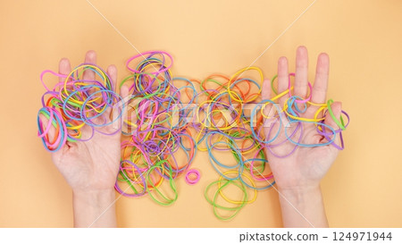 A vibrant assortment of colorful rubber bands beautifully tangled together on a peach background 124971944