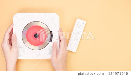 White portable CD player with remote control isolated on peach background. 124971946