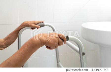Elderly woman using walker in restroom for safety. 124971968