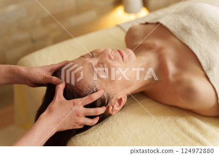 Senior woman receiving a head massage at a beauty salon Senior woman receiving a head massage at a beauty salon 124972880