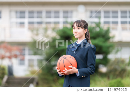 穿著校服的高中、國中和小學女生站在校園裡，手裡拿著籃球 124974915