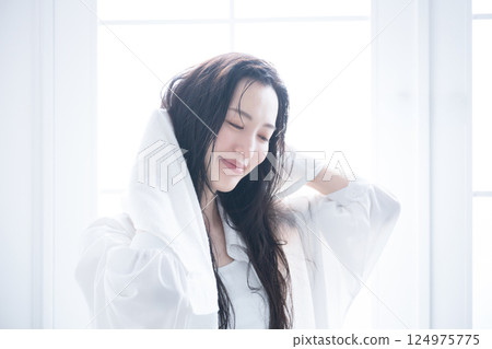 A woman towel-drying her wet hair 124975775