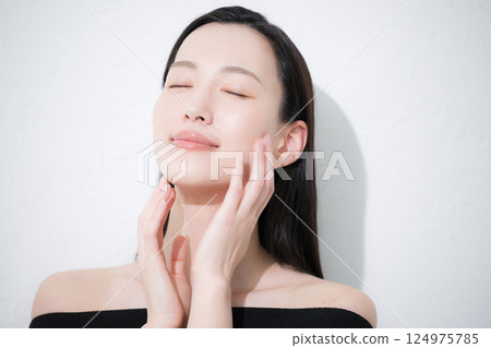 A close-up of a young woman's eyes in a beauty image of her hands holding her beautiful, shiny and natural skin 124975785