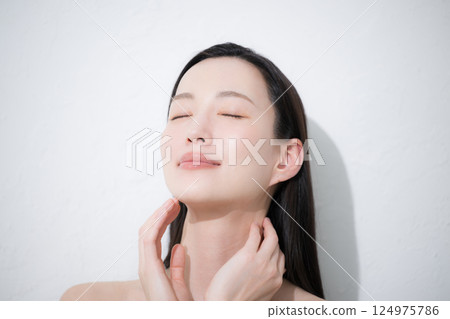 A close-up of a young woman's eyes in a beauty image of her hands holding her beautiful, shiny and natural skin A close-up of a young woman's eyes in a beauty image of her hands holding her beautiful, shiny and natural skin 124975786