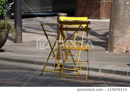Cityscape scene with cafe or rest area on the street with yellow chairs and tables Cityscape scene with cafe or rest area on the street with yellow chairs and tables 124976514