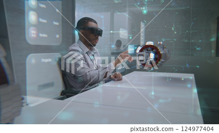 Futuristic Office: Professional Wearing VR Headset to Visualize 3D Holographic Green Energy Engine Futuristic Office: Professional Wearing VR Headset to Visualize 3D Holographic Green Energy Engine 124977404