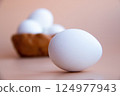 White Eggs arranged on smooth neutraltoned surface, with blurred Basket holding more eggs background. Natural Tones for Kitchen Decor Culinary Themes Diet Proteins Breakfast articles Easter themes 124977943