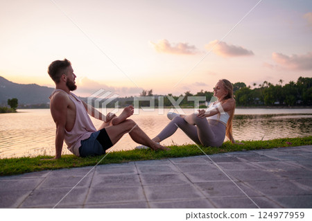 Couple Enjoying Yoga by Serene Lakeside at Sunset for Relaxation and Wellness 124977959