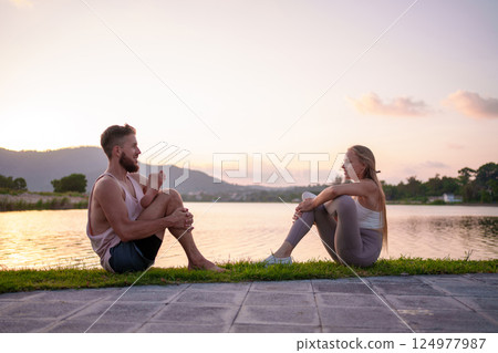 Couple Practicing Yoga by Peaceful Lakeside at Sunset for Calm and Wellness 124977987