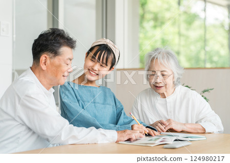 祖母和祖父看著他們的孫女學習(家庭、回家、家庭作業) 祖母和祖父看著他們的孫女學習(家庭、回家、家庭作業) 124980217