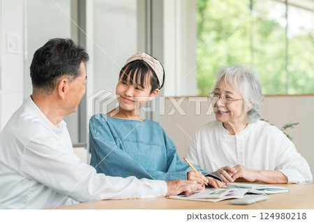 Grandmother and grandfather watching their granddaughter study (family, homecoming, homework) 124980218