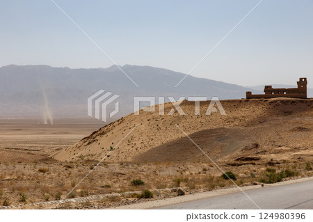 Dusty landscape and abandoned structure in the Afghan desert under a clear blue sky Dusty landscape and abandoned structure in the Afghan desert under a clear blue sky 124980396
