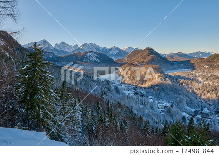 Beautiful winter morning landscape with snowy mountains and a serene lake, icy landscape surrounding majestic peaks, dawn light in January 124981844