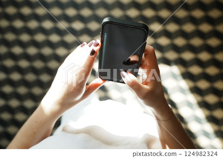 Hands Holding Smartphone with Blank Screen Above Pattern 124982324