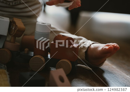 Baby Playing with Wooden Toy Train on Wooden Floor 124982387