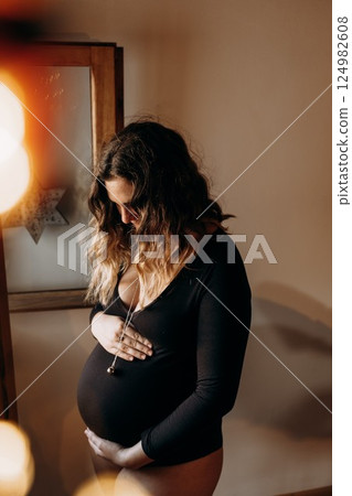 Pregnant Woman Cradling Belly in Peaceful Home Setting Pregnant Woman Cradling Belly in Peaceful Home Setting 124982608