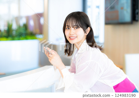 A smiling woman looking at a smartphone 124983190