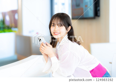A smiling woman looking at a smartphone 124983192