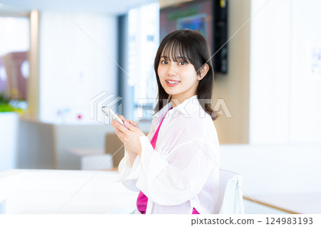A smiling woman looking at a smartphone 124983193