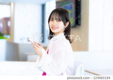 A smiling woman looking at a smartphone 124983194