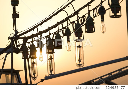 Silhouette of the lamp of an anchored squid fishing boat Silhouette of the lamp of an anchored squid fishing boat 124983477