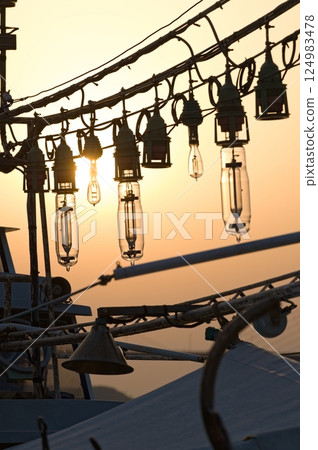 Silhouette of the lamp of an anchored squid fishing boat Silhouette of the lamp of an anchored squid fishing boat 124983478