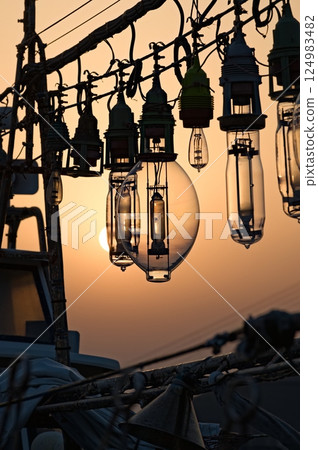 Silhouette of the lamp of an anchored squid fishing boat Silhouette of the lamp of an anchored squid fishing boat 124983482