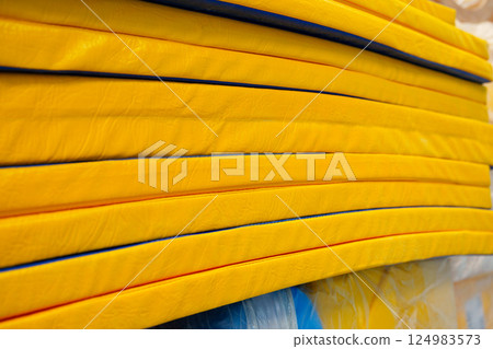 Stacked bright yellow foam mats in a training facility ready for use during gymnastics practice 124983573