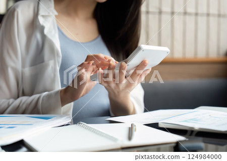 Businesswoman using a calculator and smartphone to manage financial data. 124984000