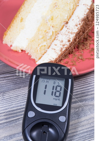 Glucose meter with result of sugar level and cake Glucose meter with result of sugar level and cake 124985723