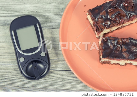Glucose meter for measuring sugar level and fresh cheesecake with cherries and chocolate Glucose meter for measuring sugar level and fresh cheesecake with cherries and chocolate 124985731